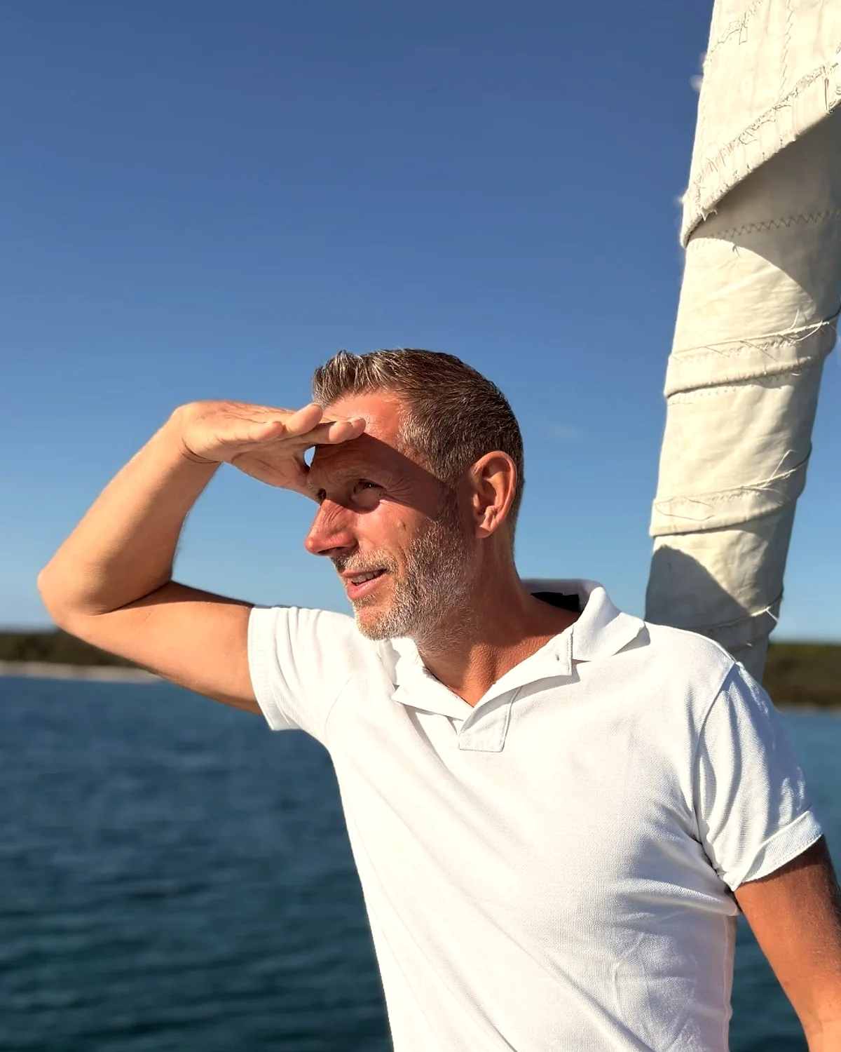 Patrick hält als Ausguck die Hand an die Stirn und blickt vom Bug eines Segelschiffs in die Ferne